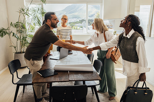 Architects greet clients with a firm handshake before a meeting.