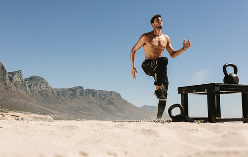 Man doing fitness training at the beach with kettlebells