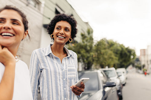 Carefree young women waiting for a taxi in the city