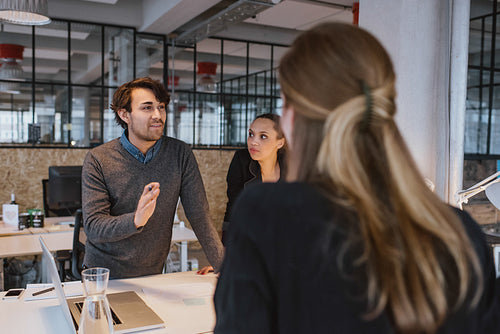 Young man explaining new business plan to coworkers 