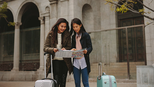 Smiling asian tourists looking at a city map