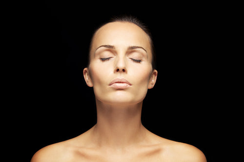 Serene young woman on black background
