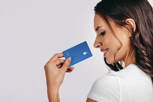 Smiling into the new era of banking: Happy woman holds a bank card in a studio