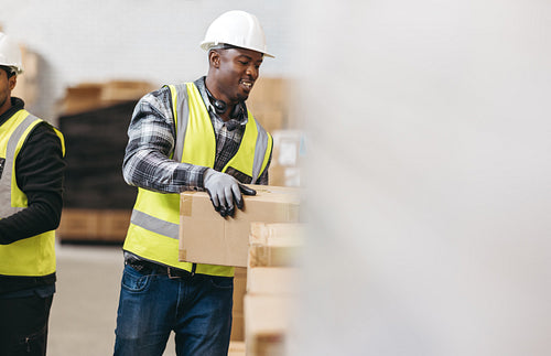 Happy young man moving cardboard boxes in a warehouse
