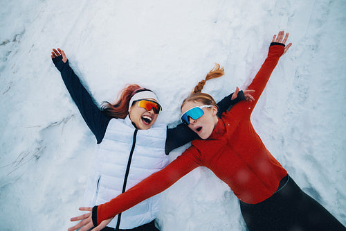 Two female athletes celebrate in snow after winter training session