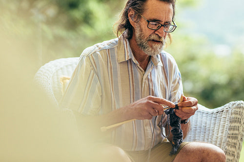 Elderly man with beard knitting