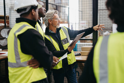 Warehouse supervisor having a discussion with his colleagues during a meeting