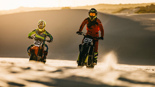 Dirt bikers racing on sand dunes