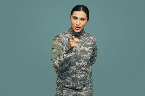 Young military servicewoman pointing at the camera in a studio