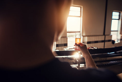 Manufacturer examining beer in glass at brewery