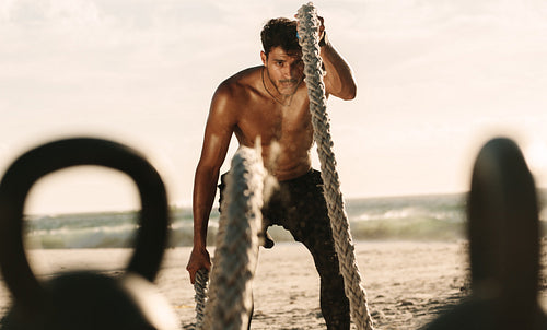 Man doing workout with battle ropes and kettlebells