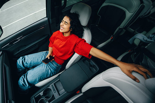 The woman enjoys a relaxing passenger moment in the car with her smartphone