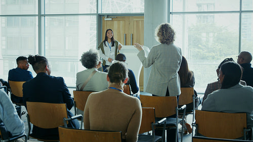 Businesswoman asking presenter a question during a dynamic conference session