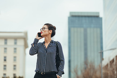 Businesswoman walking outdoors with cellphone