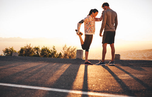 Fit young couple warming up before a run together