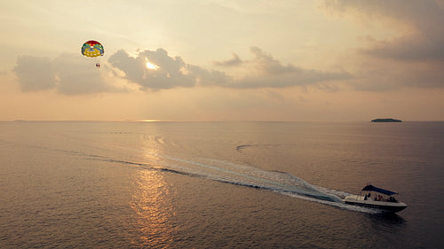 Parasailing adventure at sunset with a boat on the calm ocean