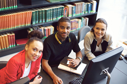 Confident young students at library using computer