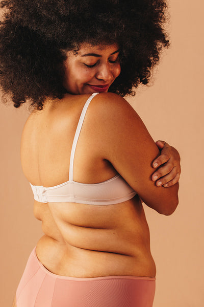 Confident plus size woman embracing herself in a studio