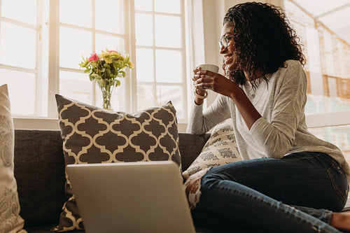 Businesswoman enjoying a cup of coffee while working on laptop