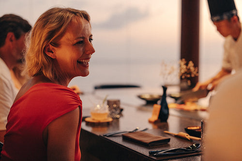 Smiling woman enjoying a gourmet dining experience at sunset restaurant