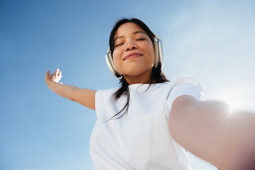 Woman enjoying music with headphones outdoors, carefree