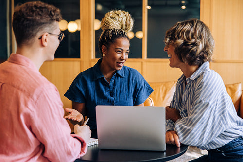 Three colleagues having a productive discussion around a laptop