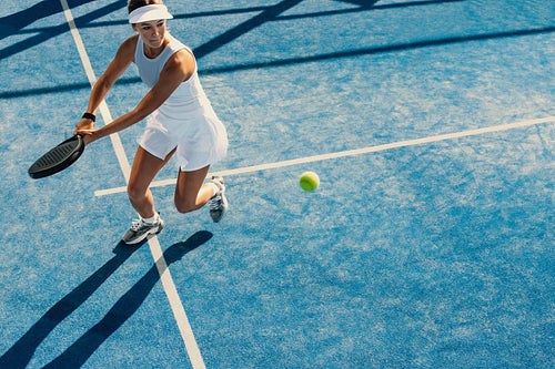 Female athlete dominates padel court with impressive two-handed backhand stroke