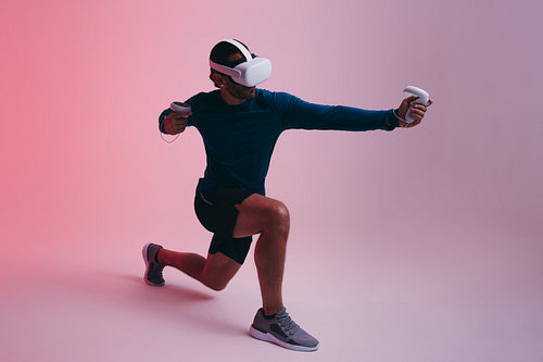 Sporty young man shooting a virtual arrow in a studio