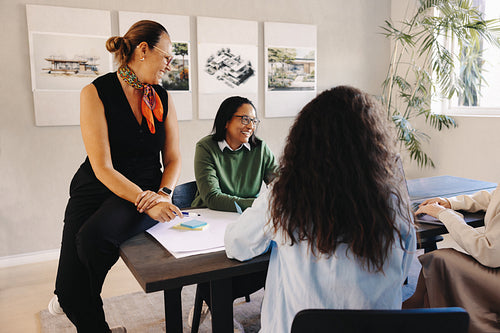Team collaborating during a casual meeting with plans and drawings displayed