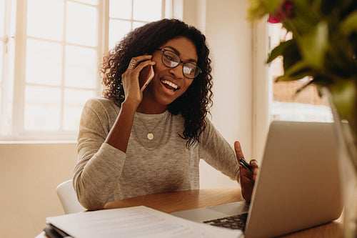 Businesswoman working from home on laptop and mobile phone