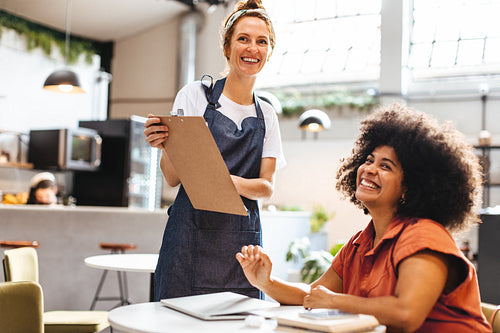Happy waitress serving a customer with the menu in a cafe