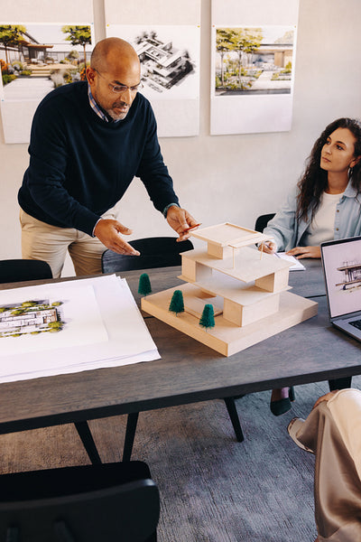 Team collaboratively discussing architectural plans and construction project model in office