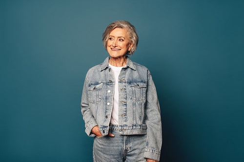 Cheerful mature woman with grey hair wearing casual denim smiling against blue background
