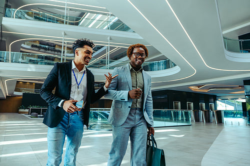 Two businessmen walking and conversing in a modern office lobby