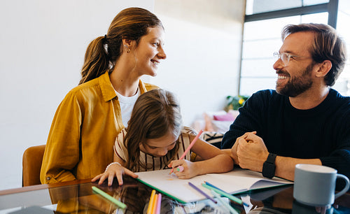 Family smiles as parents help daughter with drawing