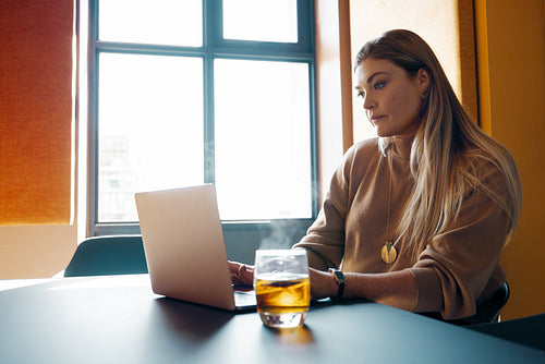 Young woman working diligently on a laptop in a modern office setting
