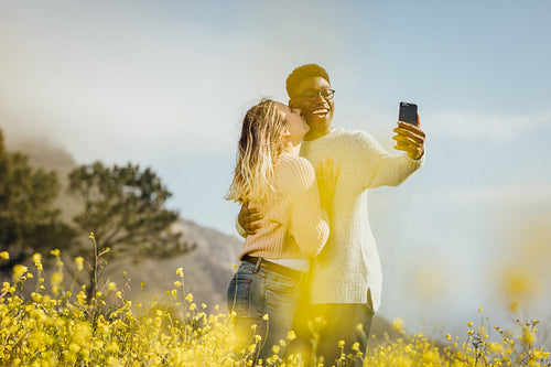 Romantic couple standing outdoors taking selfie