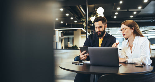 Two entrepreneurs using a digital tablet together at work