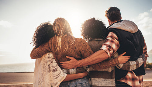 Friends standing together and looking at the sea