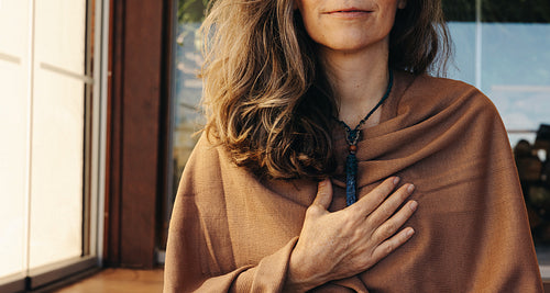 Mature woman wearing a crystal necklace at home