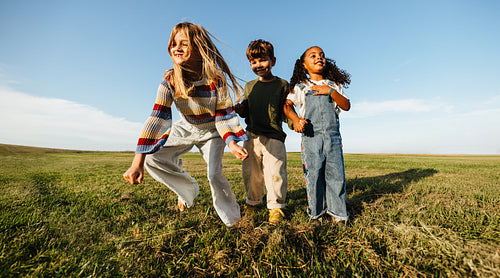 Young girl and boy run through a field
