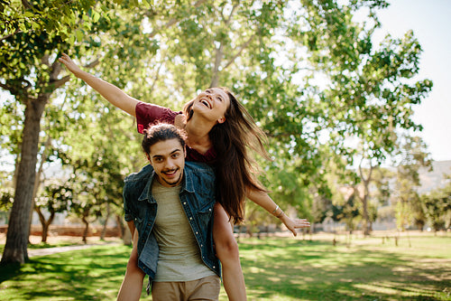 Couple piggybacking at park