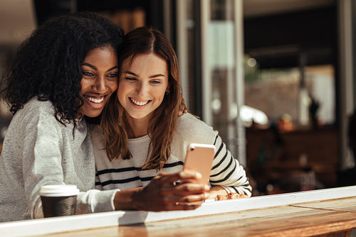 Friends sitting in a cafe taking selfie with a mobile phone