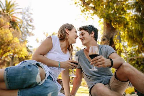 Romantic couple sitting in a park drinking wine
