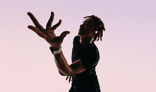 Expressive gen z male dancing to music with wireless earbuds and smartwatch in studio