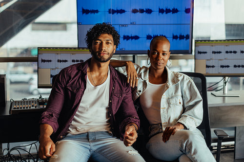 Confident creative professionals posing in a modern music studio