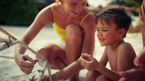 Mother and son happily learning about coral reef conservation on a beautiful sandy beach