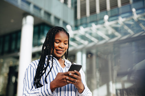 Cheerful young businesswoman using a smartphone during her morning commute in the city