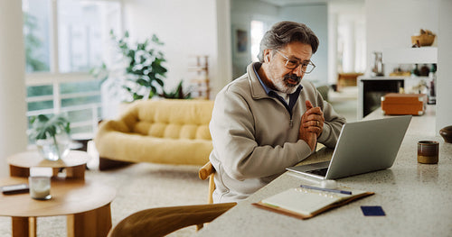 Senior man video calls on laptop at home