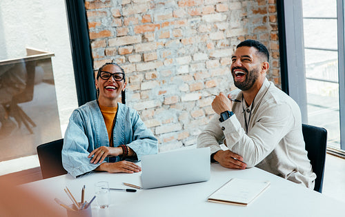 Business professionals having a lively meeting in a sophisticated business environment with a laptop and notepad